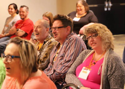 This picture shows a group listeners laughing and smiling as they attend a breakout session.