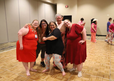 Female attendees embrace one another as they pose together for a photo.