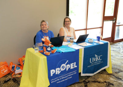 Two women from the University of Missouri Kansas City sit at a decorated table, ready to share information about their school's self-advocate program, Propel.