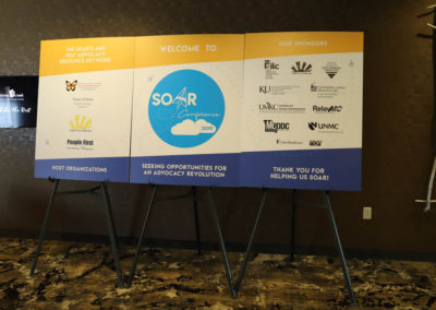 A set of three large SOAR conference posters sit side-by-side on easels, greeting conference attendees as they enter.