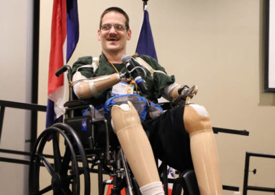 Travis Schaffer, self-advocate from Nebraska, is pictured seated on stage while presenting to the SOAR conference crowd.