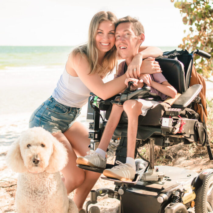 Photo of Hannah, Shane, and their Goldendoodle on the beach.