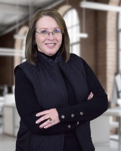 Photo of Joy Lewis. She is standing in a large open room and smiling.