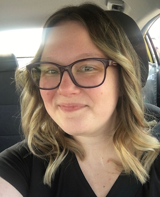 Selfie of McKenzie Mertes. She is sitting in a car and smiling.