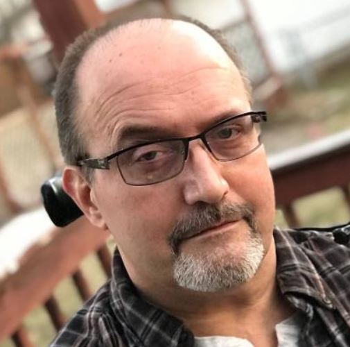 Photo of Greg Fier sitting on a porch.