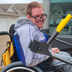 Photo of Michael Martin sitting in a wheelchair. He is looking over his right shoulder and smiling.